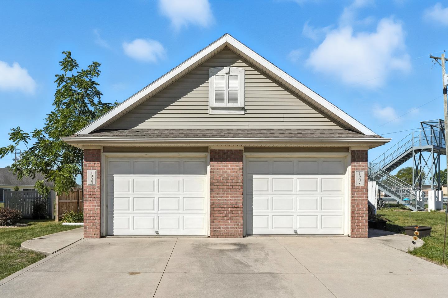 The same duplex head on, its two garage doors and two unit numbers side by side under one gable.