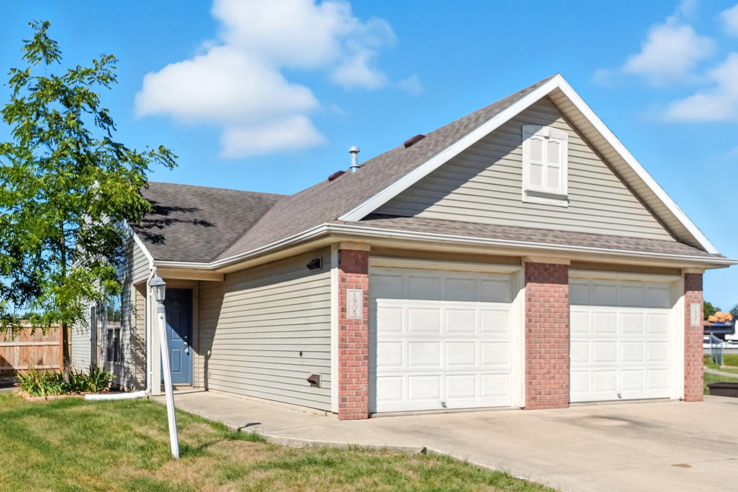 A duplex seen from its left end, with one unit's entry door beside the two garages.